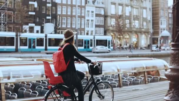 Schülerin radelt mit Fahrrad an einem Flussufer entlang. Nahpendler. Frau mit Hut cruist auf einem Stadtrad. Zeitlupe. — Stockvideo