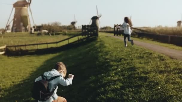 Dvě malé děti si hrají v blízkosti staré windmill farm. Šťastné děti pobíhat rustikální vesnické scenérie. Štěstí a radost. 4k