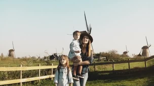 Portret rodziny Europejskiej w pobliżu gospodarstwa wiatrak. Piękna kobieta w kapeluszu z małego chłopca i dziewczyny chodzić razem. 4k. — Wideo stockowe