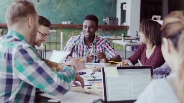 Reunión creativa del equipo de negocios en la oficina moderna. Grupo mixto de jóvenes discutiendo ideas de start-up, riéndose . — Vídeo de stock
