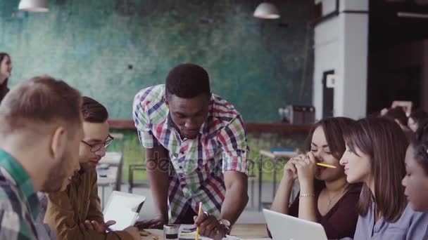 Unga multiracial grupp människor som arbetar i coworking space. Små, nystartade arkitekter diskuterar projektidéerna. — Stockvideo
