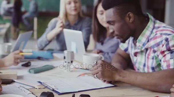 Fiatal, csinos afrikai férfi aláírja a szerződést. Embercsoport taps a háttér iroda. lassú mo — Stock videók