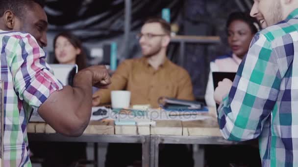 Equipo de negocios joven trabajando juntos cerca de la mesa, lluvia de ideas. Dos hombres se saludan con el puño. . — Vídeo de stock