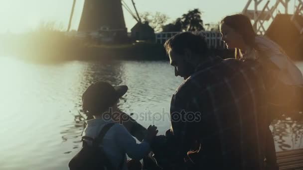 Чоловік з двома дітьми сидить разом біля води. Час сімейного зв'язку. Говорячи і роздумуючи. Щасливі дитячі спогади 4K . — стокове відео