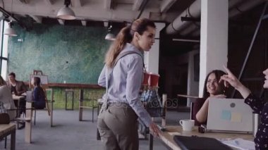 Esmer kadın Yöneticisi modern ofis iş başında gelir. Genç kadın meslektaşları ile selamlıyor, arkadaşıma kahve getiriyor.