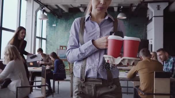 Morena gerente feminina vem ao escritório moderno no trabalho. Mulher jovem cumprimenta com colegas, traz café ao amigo . — Vídeo de Stock