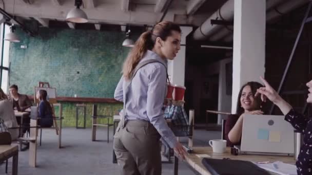 Brunette vrouwelijke manager gaat om moderne kantoor op het werk. Jonge vrouw begroet met collega's, brengt koffie aan vriend. — Stockvideo