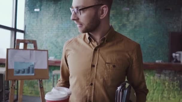 Gutaussehender Geschäftsmann kommt bei der Arbeit ins moderne Büro. Junger Mann grüßt mit Kollegen, bringt Kaffee zu Freundin — Stockvideo