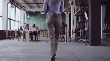 Esmer kadın Yöneticisi modern ofise geliyor. Genç kadın meslektaşları ile selamlıyor, arkadaşıma kahve getiriyor. yavaş mo