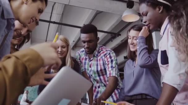 Jeune équipe travaillant sur un nouveau projet. Groupe de personnes de race mixte debout près de la table et discutant .
