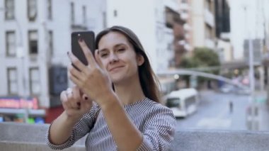 Genç güzel kadın smartphone selfie fotoğraf çekmek. Trafik yol ve arka planda meşgul cityscape.