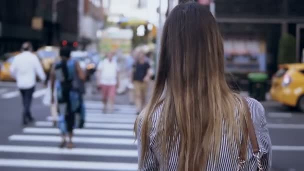 Baksidan på ung snygg kvinna promenader i centrum, kvinnliga korsande väg, går igenom publiken i New York — Stockvideo