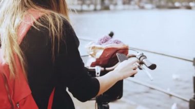 Yaratıcı iş kadını bir köprüde fotoğraf çeker. Bisiklet üzerinde şık Bayan güzel nehir şehir sahne fotoğraflar. 4k.