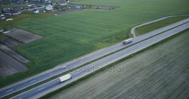 Panorama aéreo de autopista con campo y pueblo. Drone 4K panning tilt shot. Industria de redes de transporte logístico . — Vídeos de Stock