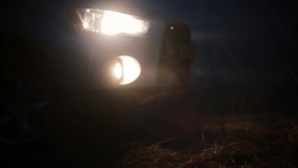 Alacsony szög autó első fényszóró a éjszaka. Titokzatos gyönyörű kilátás. Foltos bokeh sötét háttér absztrakt lövés. — Stock videók