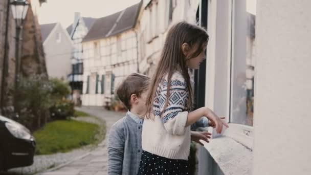 Fajny chłopak i dziewczyna wybrać prezenty w storefront zabawka. Dwoje dzieci Kaukaska stoją, zakupy okno. Hattingen, Niemcy. 4k. — Wideo stockowe