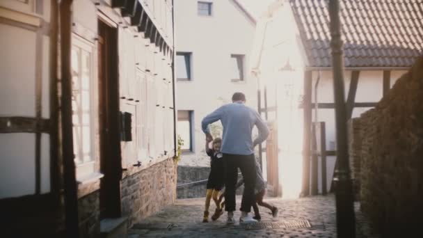 Vader dansen roundelay met twee gelukkige jonge geitjes. Kaukasische man neemt jongen en meisje in zijn armen, ze kussen en glimlacht. 4k. — Stockvideo