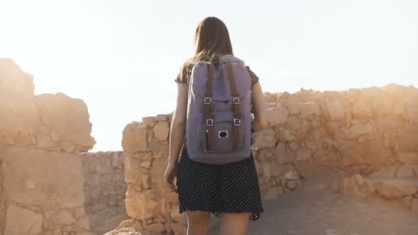 Flicka med ryggsäck utforskar öken fornlämningar. Vacker kvinna promenader bland bergen fästningens murar i Masada, Israel. 4k — Stockvideo