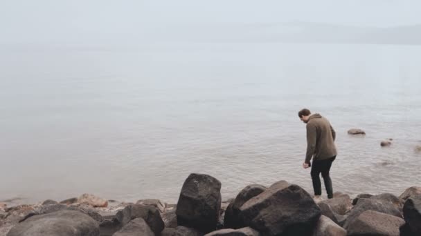 ガリラヤの海の端に白人男。キブツ ・ キネレット湖ティベリウスの大きな石の海岸。イスラエル。宗教的な巡礼者。4 k. — ストック動画