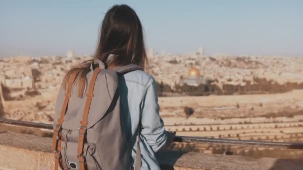 Europees meisje met grijze rugzak geniet van Jeruzalem. Vrouwelijke toeristische kijkt naar de oude binnenstad in Israël van een skydeck. 4k — Stockvideo