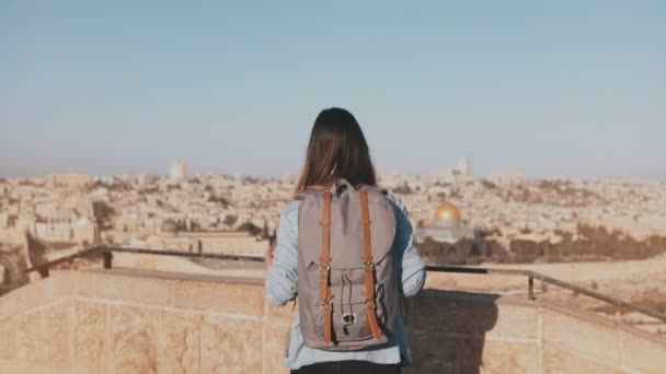 Girl with backpack walks to see old Jerusalem town. Excited European tourist raises hands joyful and happy. Israel. 4K. — Stock Video