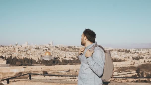 Opgewonden Europese toeristische mannelijke kijkt rond. Israël, Jeruzalem. Gelukkig Glimlachende man met rugzak heeft prachtig uitzicht 4k. — Stockvideo