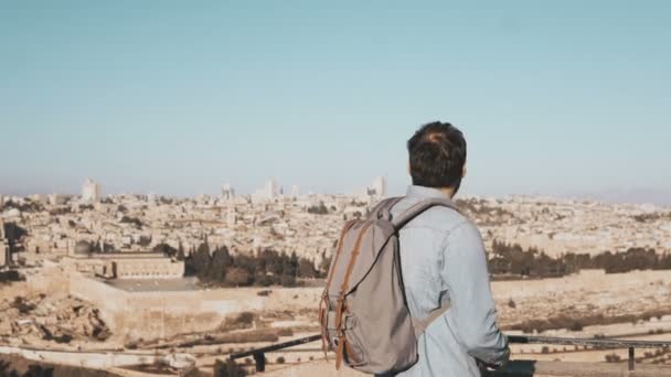 Toeristische mannelijke neemt foto's van panorama van Jeruzalem. Man met een rugzak staat aan skydeck rand met smartphone. Israël 4k. — Stockvideo
