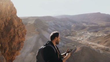 Adam inanılmaz çöl manzara fotoğraflarını çeker. Kameraya büyük dağ manzarası ile Avrupa erkek turist. İsrail 4k.