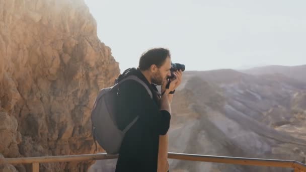O homem tira fotos de enormes paisagens montanhosas. Homem caucasiano com fotografias de câmara e olha para a câmara. Israel 4K . — Vídeo de Stock