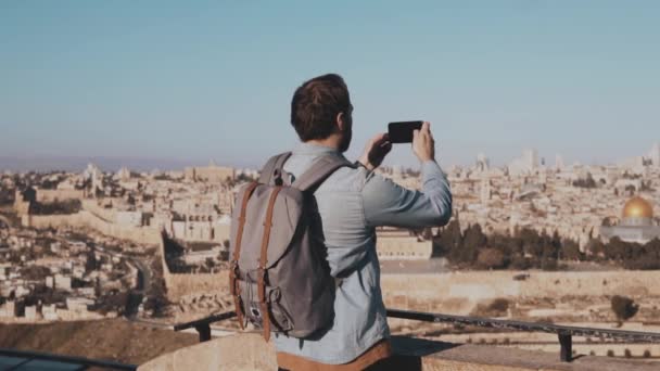 男性の観光客は、エルサレムのスマート フォンの写真をとります。ヨーロッパのひげを生やした男は、古代の町の風景を楽しんでいます。イスラエル。スローモーション — ストック動画