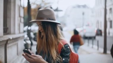 Browsing belgili tanımlık enterne Paris, Fransa için sokaktaki ayakta ve belgili tanımlık smartphone kullanarak genç güzel kadın.