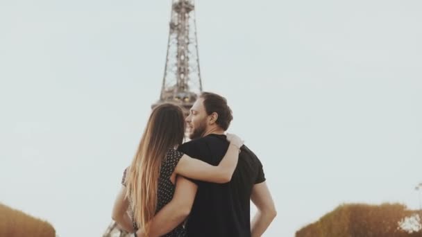 Young happy couple walking near the Eiffel tower in Paris, France. Man and woman look and monument and rising hands. — Stock Video