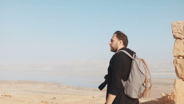 Kavkazská muž má úžasný komplexu Dead Sea panorama. Nadšený fotograf stojí na vrcholu hory s kamerou Izrael Masada 4k — Stock video