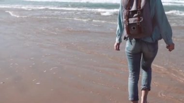 Kız deniz kıyı yürüyor, suda taş atar. Özgürlük kavramı. Saç esen rüzgar. Tatil keyfi. Ağır çekim