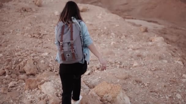 La chica camina sobre una gota del desierto. En cámara lenta. Mujer joven deambula en grandes rocas abismo y piedras. Peligroso camino arriesgado . — Vídeos de Stock