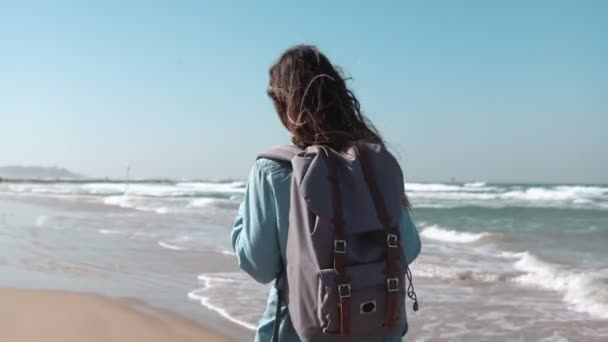 Tjej går på sommaren havet stranden tänkande om livet. Frihet och retreat koncept. Vinden blåser i håret. Fantastisk sky. 4k — Stockvideo