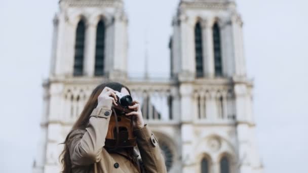 Beautiful teenager female taking photos of Notre Dame on retro film camera in Paris, France, famous cathedral. — Stock Video