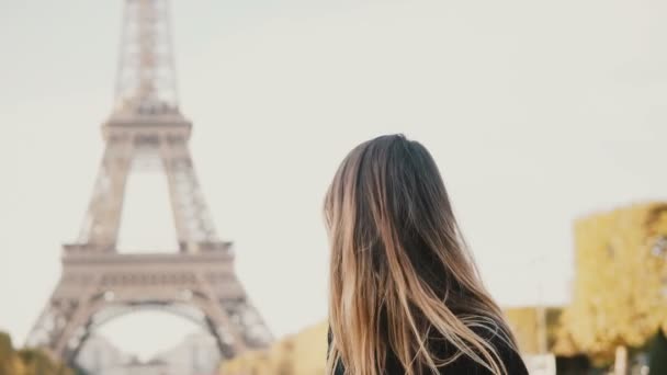 Retrato de uma jovem bela mulher em pé perto da Torre Eiffel, em Paris, França, olhando para a câmera e sorrindo . — Vídeo de Stock