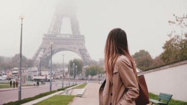 Fransa'nın Paris, Eyfel Kulesi yakınındaki yürüyen genç mutlu kadın. Etrafa ve gülümseyen turist. Ağır çekim.