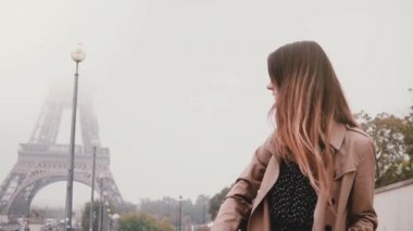 Tek başına ayakta ve Eyfel Kulesi Paris, Fransa'da sisli sabah erkenden seyir genç şık kadın. Ağır çekim.