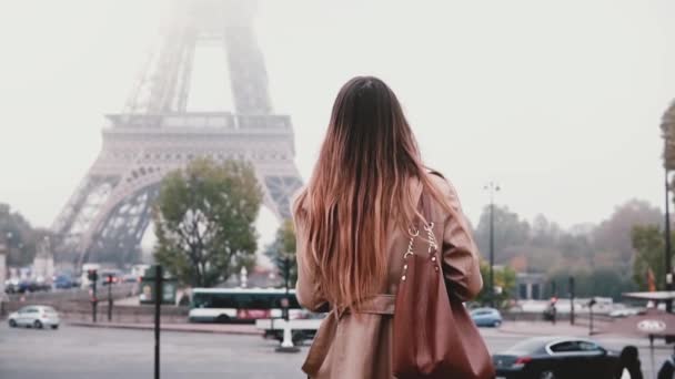 Mujer joven y elegante tomando fotos de la torre Eiffel en la niebla en el teléfono inteligente. Chica viajando en París, Francia solo . — Vídeos de Stock