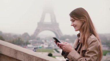 Yukarı ve Fransa'nın Paris, Eyfel Kulesi yakınındaki smartphone kullanarak genç şık kadın. Ağır çekim.