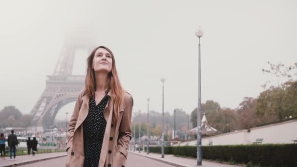 Ung attraktiv kvinna promenader nära Eiffeltornet i Paris. Glad tjej tittar och ler. Slow motion. — Stockvideo