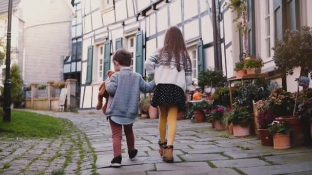 Dos niños caminan juntos a lo largo de edificios antiguos. Chica y niño exploran la hermosa ciudad vieja alemana. Juntos y amor — Vídeo de stock