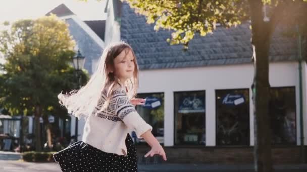 Mooie Kaukasische meisje gelukkig spinnen. Slow-motion. Fel zonlicht in lang haar. Weinig vrouwelijke kind dansen, lachen. — Stockvideo