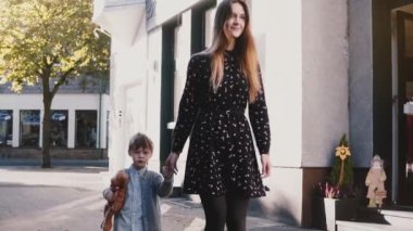 Anne küçük çocuk ile birlikte yürür. Tutan eller. Ağır çekim. Çok Avrupa kadın çocukla vakit geçiriyor. Tatil.