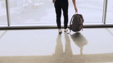 Kadın sırt çantası ile Havaalanı penceresine yürür. Mutlu başarılı Avrupa yolcu Terminal smartphone kızla. 4k.