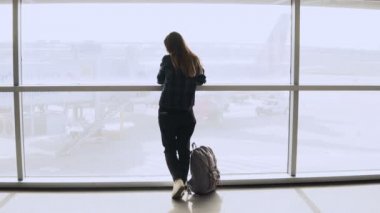 Genç kız selfie fotoğraf Havaalanı pencere alır. Sırt çantası ile mutlu Avrupa turizm smartphone terminalde kullanır. 4k.