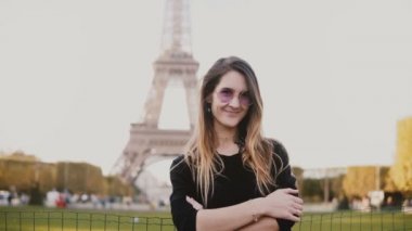 Fransa'nın Paris, Eyfel Kulesi yakınındaki genç güzel kadın portresi. Kadın kameraya bakarak ve gülümseyen,