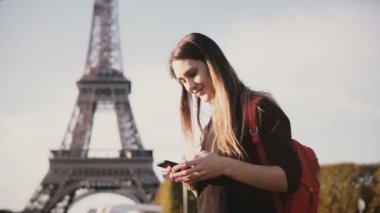Paris, Fransa'da Eyfel Kulesinin yakınında duran ve smartphone kullanarak genç güzel kadın. arkadaşlarınızla konuşurken.